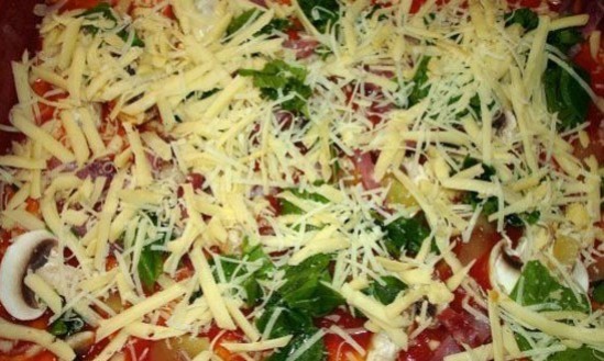 Выложите ингредиенты на будущую пиццу, а сверху посыпьте тертым сыром.