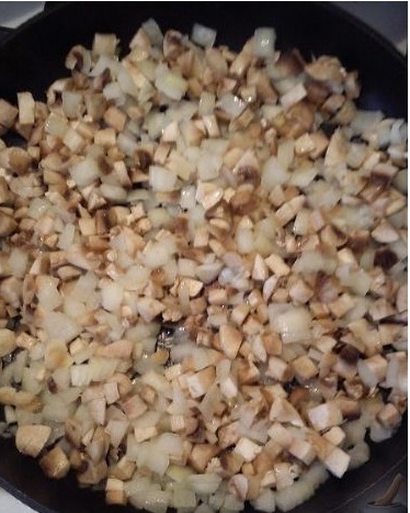 На разогретой сковороде жарим шампиньоны с луком до тех пор, пока не испарится влага от грибов.